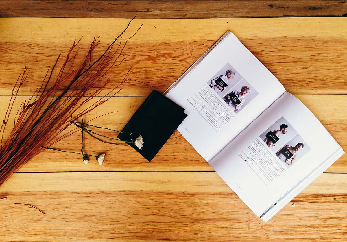 business card high-angle photo of opened book near red decorative twigs on table text